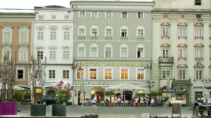 Eine Gruppe von Menschen sitzt vor dem Hotel wolfinger