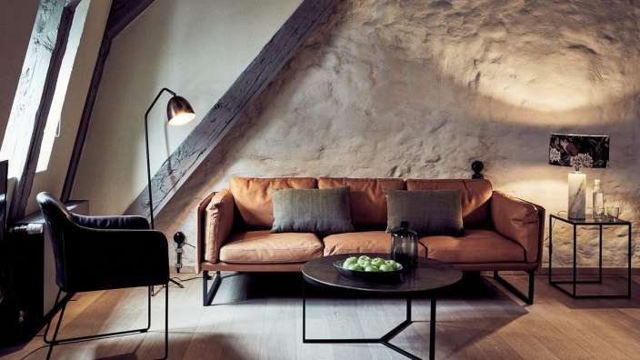 Ein Wohnzimmer mit einem braunen Ledersofa und einem schwarzen Stuhl