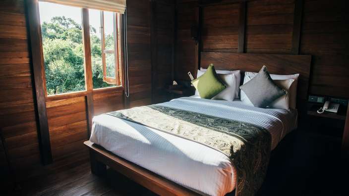 Ein Holzschlafzimmer mit einem Bett und einem Fenster