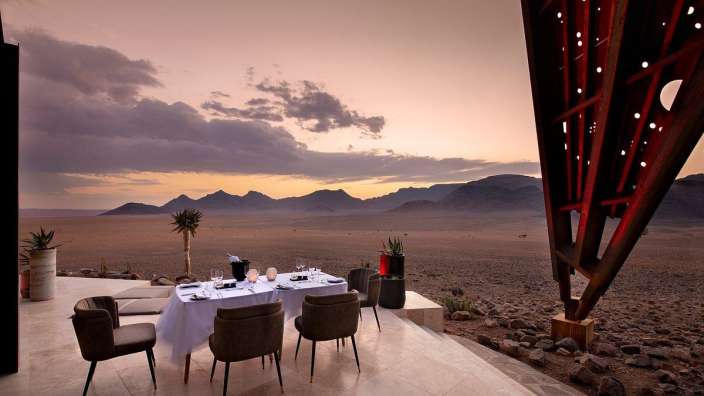 Ein Tisch und Stühle in der Wüste bei Sonnenuntergang