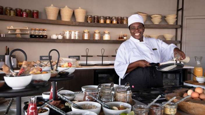 Ein Koch bereitet Essen in einer Küche und lächelt