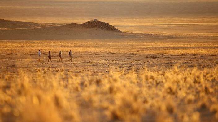 Eine Gruppe von Menschen geht durch eine Wüste