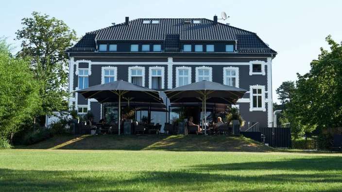 Ein großes schwarz-weißes Gebäude mit vielen Sonnenschirmen davor