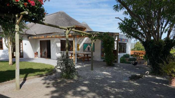 Ein weißes Haus mit einem Strohdach und einem Picknicktisch