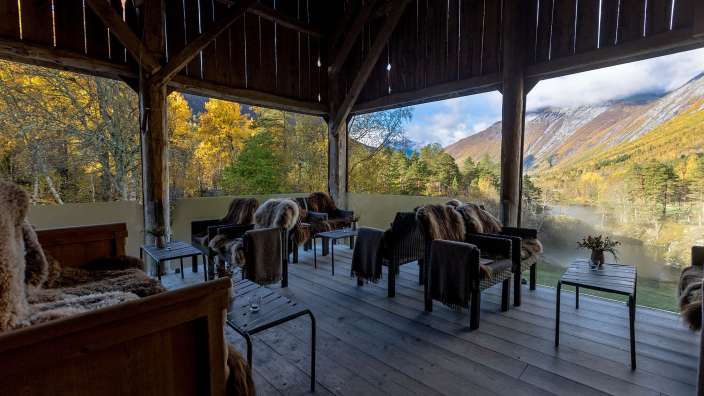 Eine hölzerne Veranda mit Stühlen und Tischen mit Blick auf die Berge