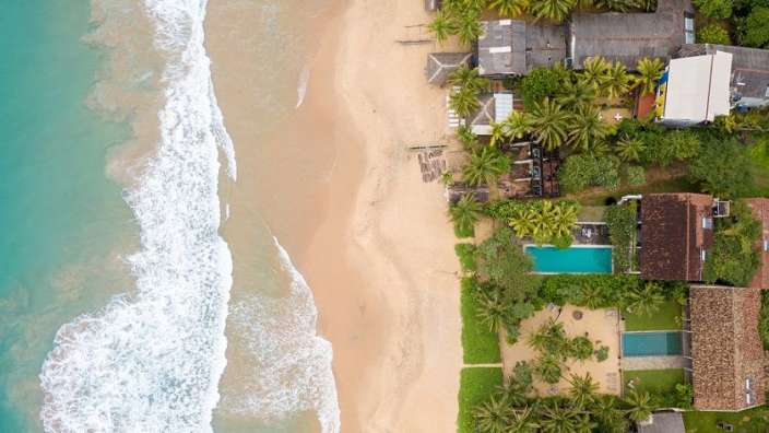 Eine Luftaufnahme eines Strandes mit Bäumen und Häusern