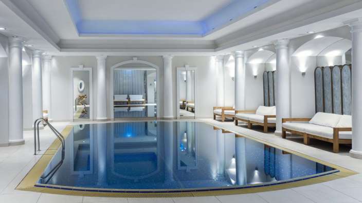 Ein großer Swimmingpool in einem Raum mit weißen Säulen