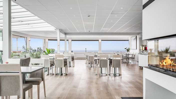 Ein Esszimmer mit vielen Tischen und Stühlen und einem Kamin