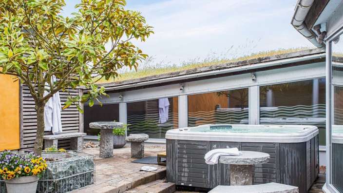 Ein Whirlpool sitzt auf einem Steintisch neben einem Baum