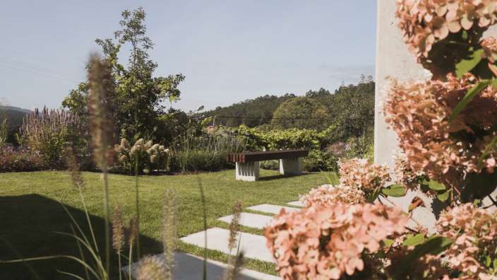 Ein Garten mit einer Bank und Blumen im Vordergrund