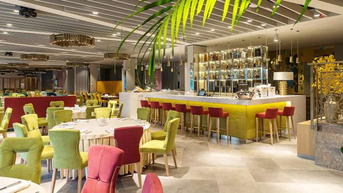 Ein Restaurant mit bunten Stühlen und Tischen und einer gelben Bar