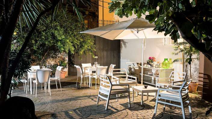 Eine Terrasse mit weißen Stühlen und Tischen und einem weißen Regenschirm