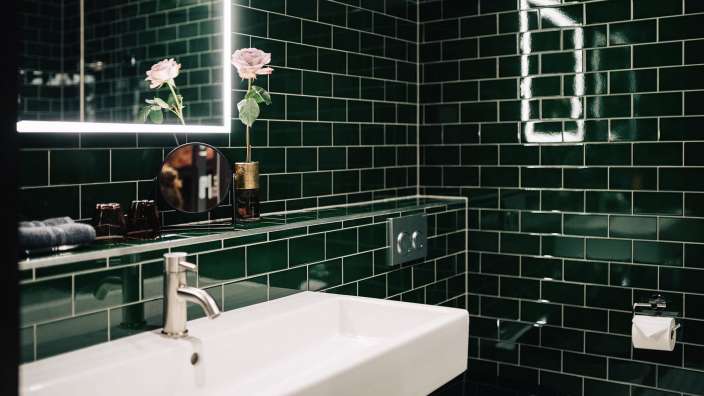 Ein Badezimmer mit grünen Fliesen und einem Waschbecken