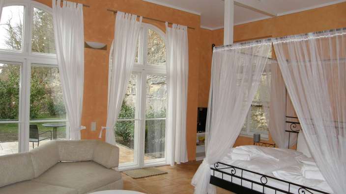 Ein Schlafzimmer mit einem Himmelbett und vielen Fenstern