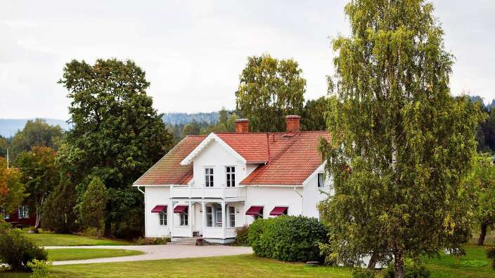 Ein weißes Haus mit einem roten Dach und roten Fensterläden