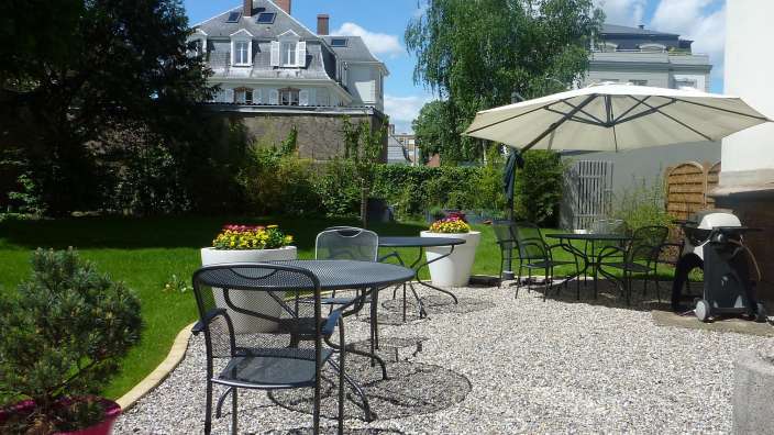 Eine Terrasse mit einem Tisch und Stühlen und einem Regenschirm