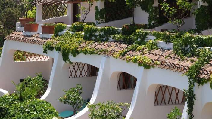 Ein weißes Gebäude mit einem braunen Dach und vielen Pflanzen darauf