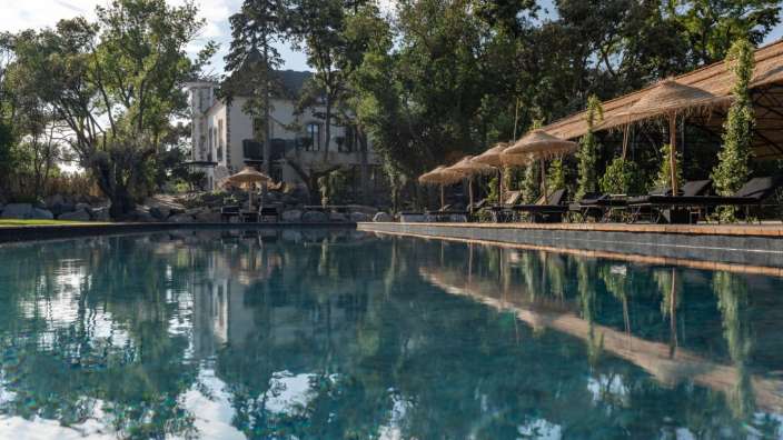 Ein großer Swimmingpool mit Liegestühlen und Sonnenschirmen umgeben