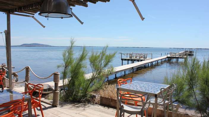 Tische und Stühle auf einem Deck mit Blick auf das Meer