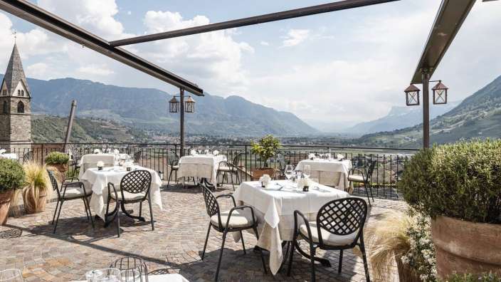 Tische und Stühle auf einer Terrasse mit Blick auf die Berge
