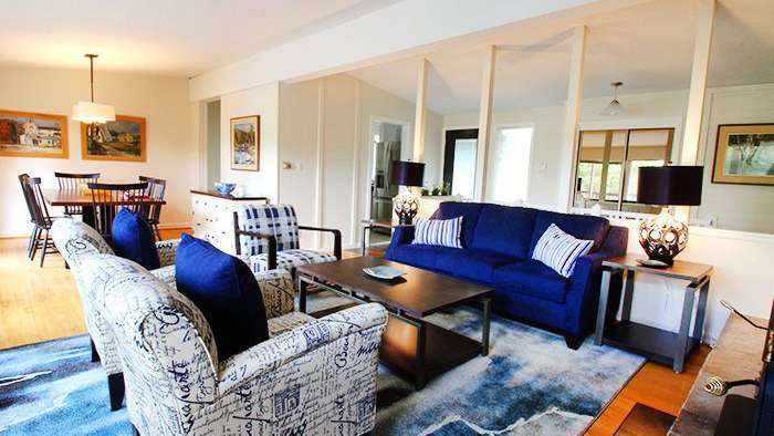 Ein Wohnzimmer mit einer blauen Couch und zwei Stühlen