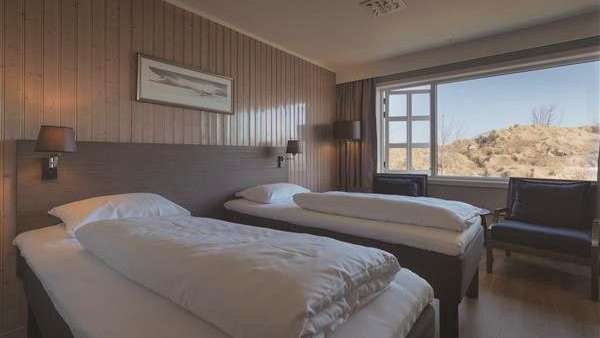 Ein Hotelzimmer mit zwei Betten, einem Stuhl und einem Fenster .