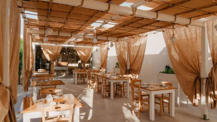 Ein Restaurant mit Holztischen und Stühlen und braunen Vorhängen