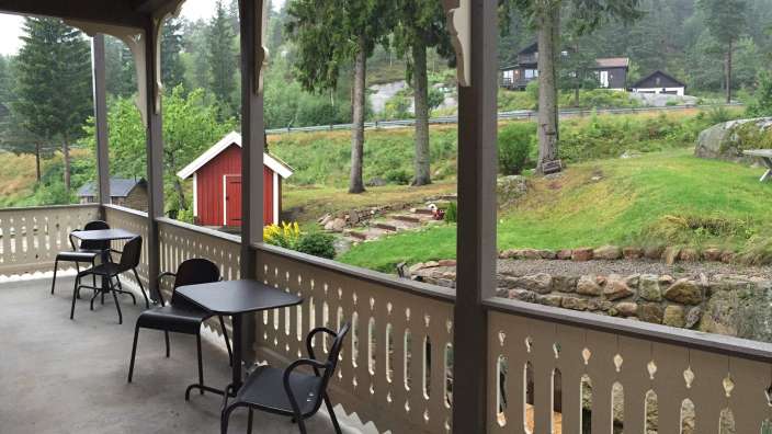 Eine Veranda mit Tisch und Stühlen und einem kleinen roten Schuppen im Hintergrund