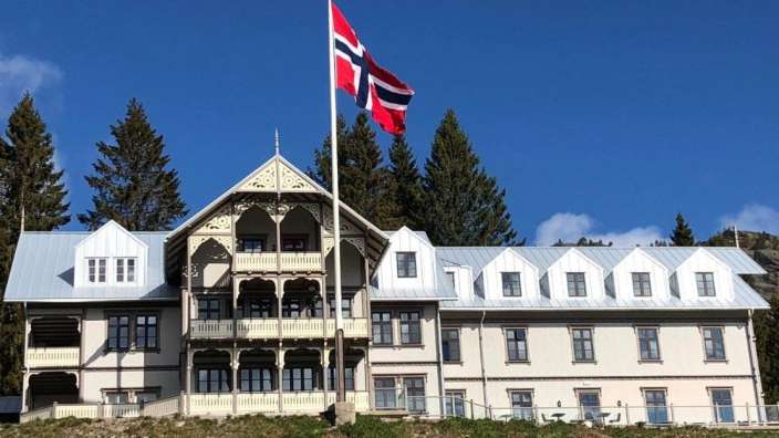 Eine norwegische Flagge weht vor einem großen weißen Gebäude