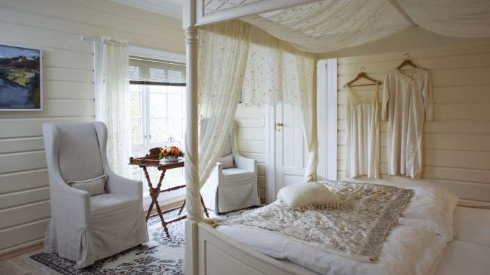 Ein Schlafzimmer mit Himmelbett und weißem Stuhl