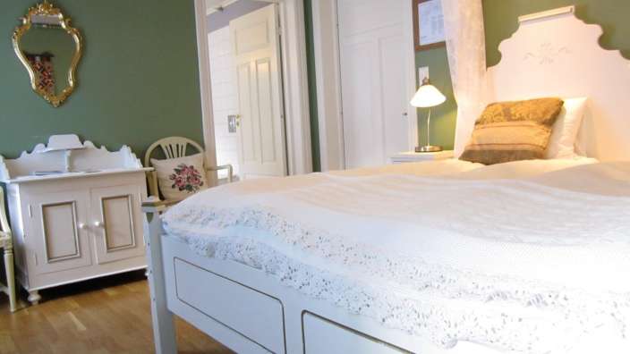 Ein Schlafzimmer mit weißem Bett und grünen Wänden