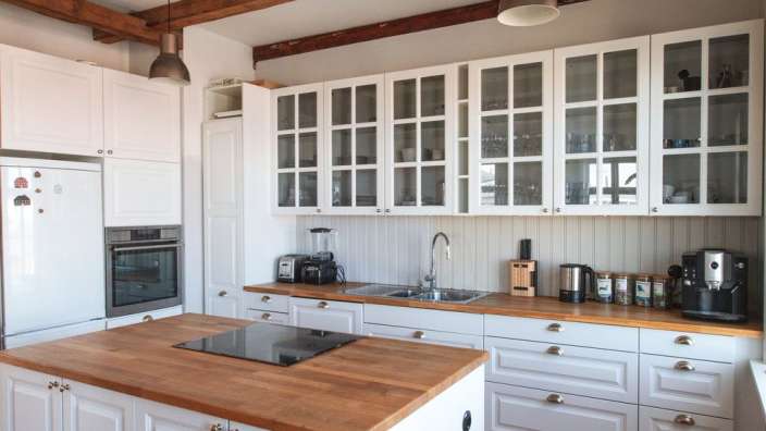 Eine Küche mit weißen Schränken und Holzarbeitsplatten