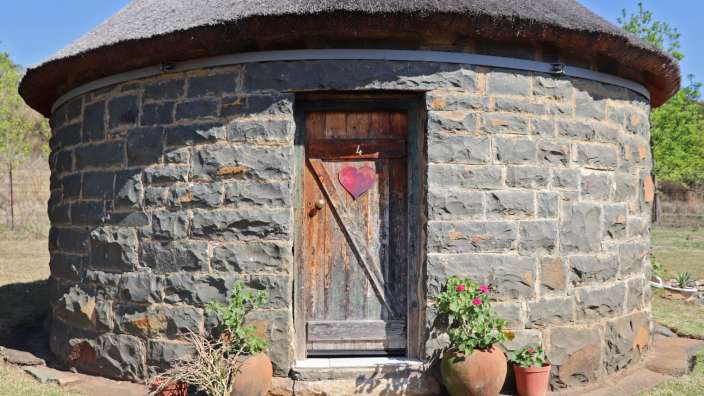 Ein Steingebäude mit Strohdach und einer Holztür mit einem Herz darauf