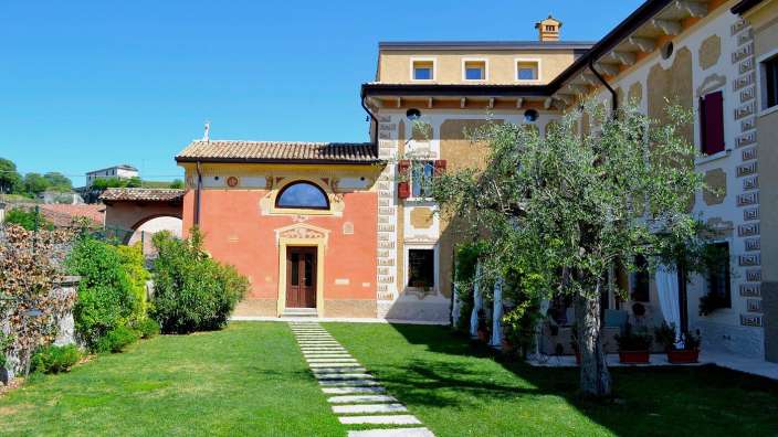 Ein Haus mit einer roten Fassade und einem gelben Haus nebeneinander