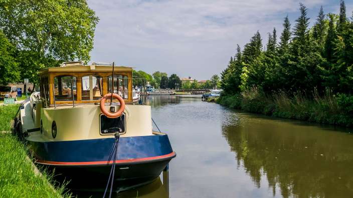 Ein blau-weißes Boot mit einem weißen Ring am Bug steht an einem Fluss