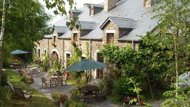 Ein Steinhaus mit Tisch und Stühlen und Regenschirmen vorne .
