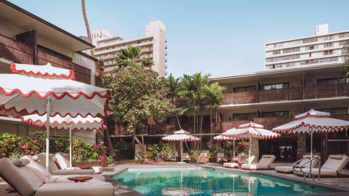 Ein großer Pool mit roten und weißen Regenschirmen umgeben