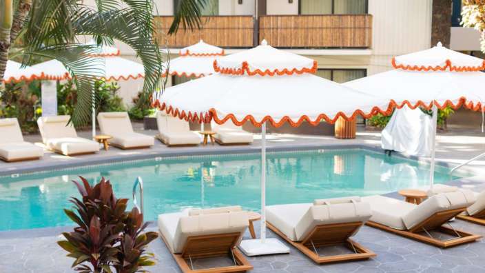 Liegestühle und Sonnenschirme um einen Pool in einem Hotel