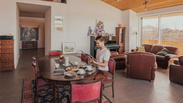 Ein Mann sitzt an einem Esstisch und benutzt ein Tablet