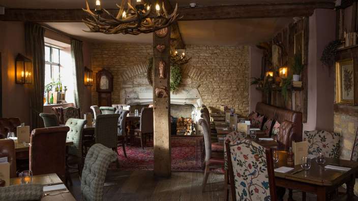 Ein Esszimmer mit Tischen und Stühlen und einem Kronleuchter mit geweihten Hörnern