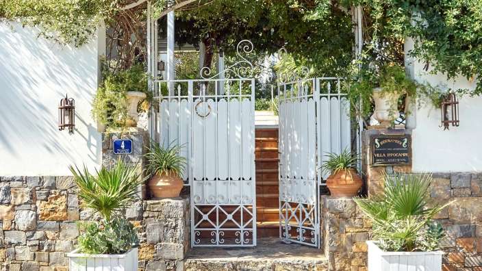 Ein weißes Tor führt zu einer Villa