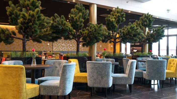 Ein Restaurant mit bunten Stühlen und Tischen und Bäumen im Hintergrund