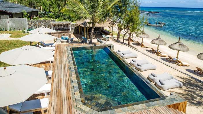 Ein großer Swimmingpool auf einem Holzdeck neben einem Strand