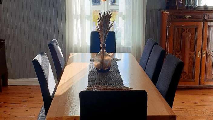 Ein Esszimmer mit einem langen Holztisch und schwarzen Stühlen