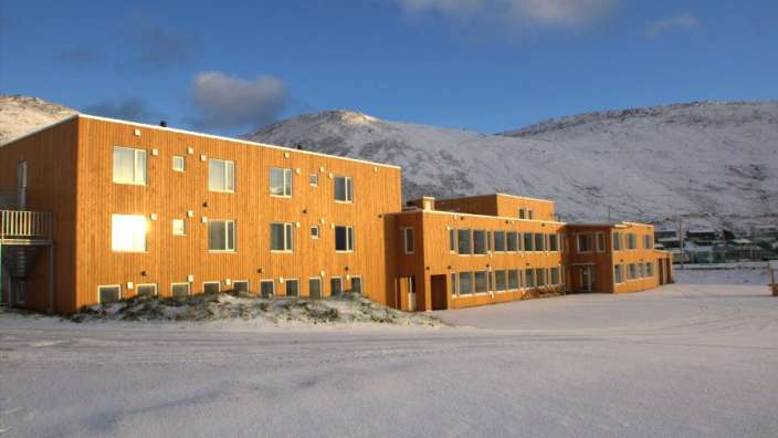 Ein großes Holzgebäude mit vielen Fenstern und einem schneebedeckten Berg im Hintergrund