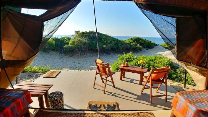Ein Tisch und Stühle in einem Zelt mit Blick auf den Ozean