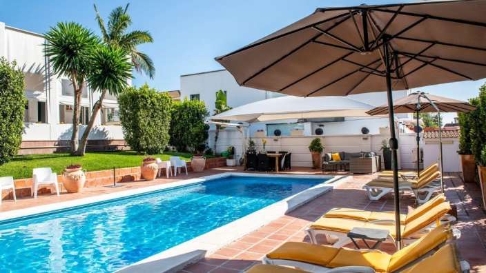 Liegestühle und Sonnenschirme umgeben einen großen Swimmingpool