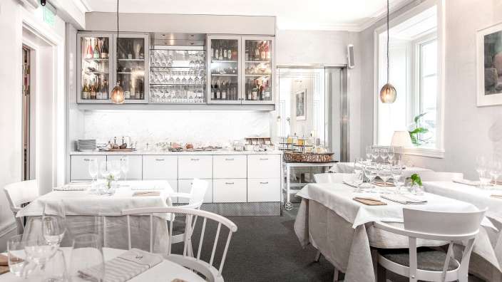 Ein Esszimmer mit weißen Tischen und Stühlen