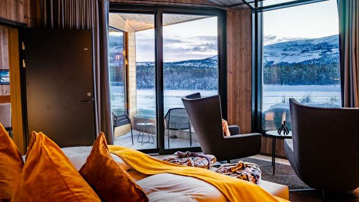 Ein Raum mit einem großen Fenster und einem Bett mit gelben Kissen