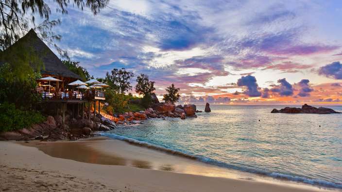 Ein Sonnenuntergang am Strand mit einem Restaurant im Hintergrund